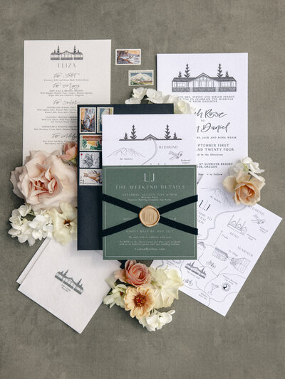 Wedding invitation flatlay with custom calligraphy, map details, florals, wax seals and ribbon