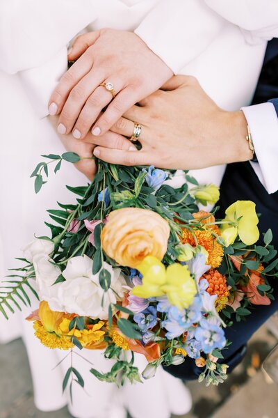 Bride and groom hold hands over couquet