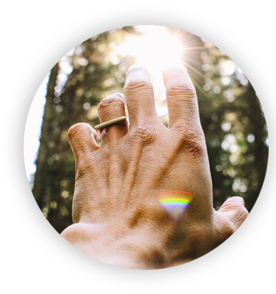 left hand with ring reaching toward light between trees