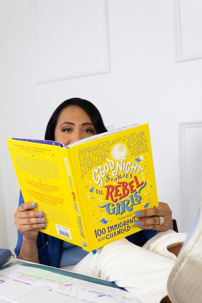 Bilingual professional coach reading a yellow branded book for kids, inspiring learning and growth