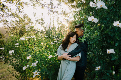 couple standing in flowers for engagement photo