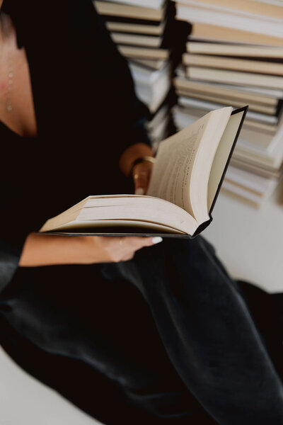 A person reading a book, surrounded by stacks of knowledge, symbolizing resources for healing and enlightenment.