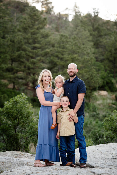 Happy parents stand on a trail smiling with their toddler son and daughter