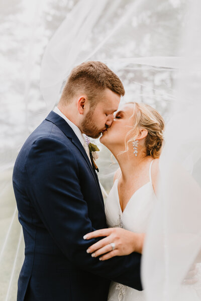couple kiss underneath brides veil