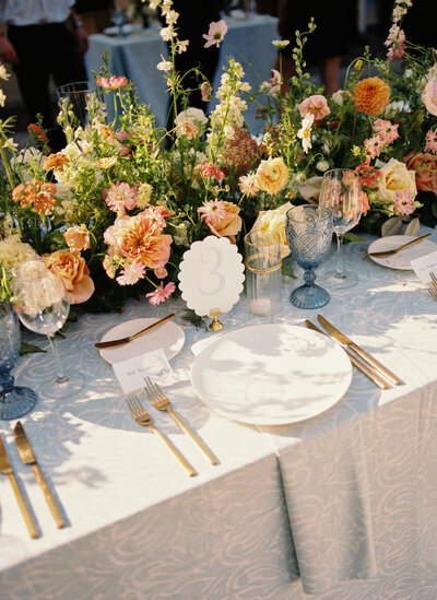 A moment captured by a film wedding photographer of a elegant tablescape at a wedding reception of pastel flowers and blue patterned linens in Charleston SC