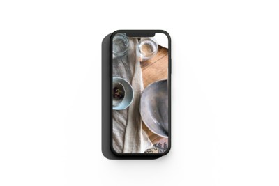 mockup of a smartphon showcasing the preset action on a wooden table with linen cloths, glasses and ceramic pieces