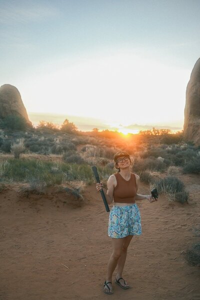 Person sitting on a large rock overlooking the rugged desert landscape of Big Bend, capturing the view with a camera — Big Bend elopement photographer capturing scenic moments in nature.