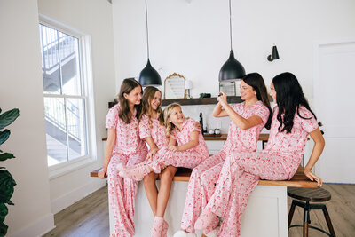 Group of sisters sitting on kitchen counter in matching Christmas pajamas.