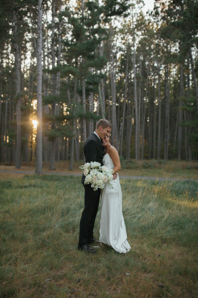 bride and groom in field of flowers and trees