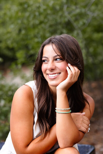 Girl puts hand on face while smiling off to the side.