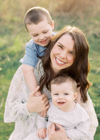 young mom holds two young sons and smiles for camera at lake hefner