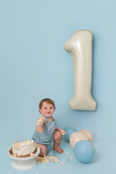 One year old with balloons and cake during cake smash photoshoot