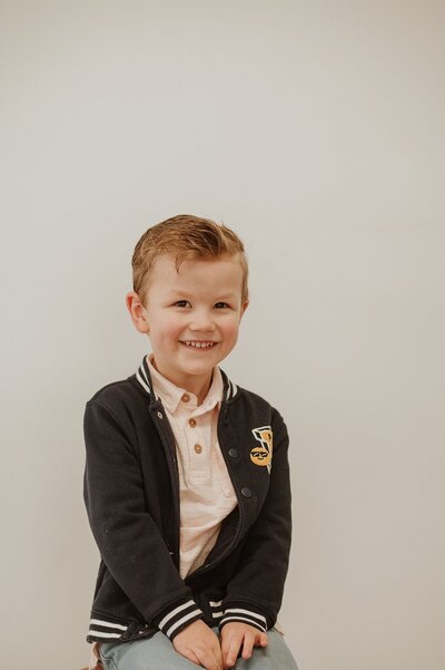 Little boy sitting in a studio with a big smile on his face