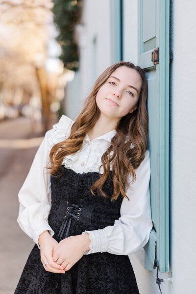 senior girl standing by colorful windows in Downtown Charleston