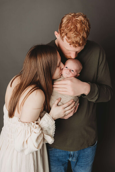 newborn boy sleeping on his tummy on a green backdrop with a tiny newborn sleepy cap in harrisburg pa newborn session