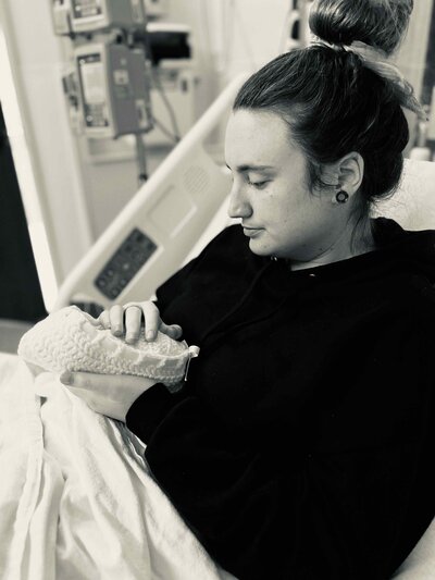 grieving mom holds stillborn baby in knit crochet cradle