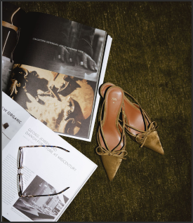 Beautiful photography magazines laying on the ground open next to kitten heels.