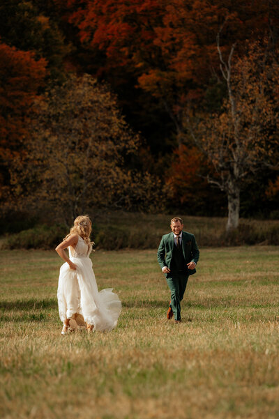 A groom chasing the bride in a field during autumn in the Adirondack mountains.