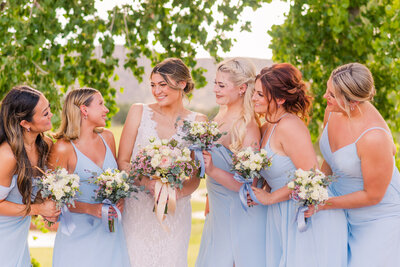 bride smiling at bridesmaids in light blue dresses at golf course wedding