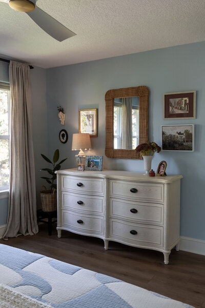 A white dresser with a gallery wall above it.