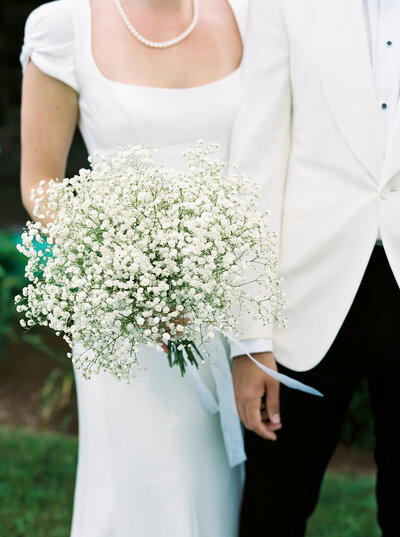 This is a close up of the bride and groom and her bouquet as they are posing for a portrait.