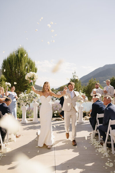 couple holding hands and smiling as they walk back down the aisle after ceremony