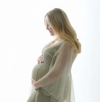 Madison's side profile accentuates her baby bump while wearing a sheer flowing golden robe. Photo by Beth Benecki.