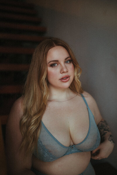 plus size girl in a blue bralette sitting in a stairway