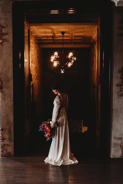 a photo of a bride standing in front of an ornate staircase holding her bouquet