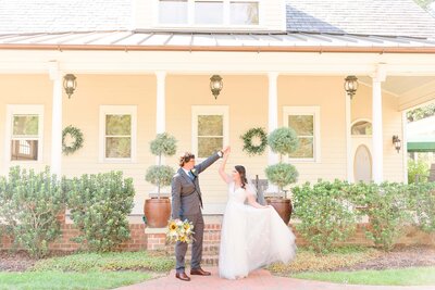 A bride and groom twirl in front of Alexander Homestead.