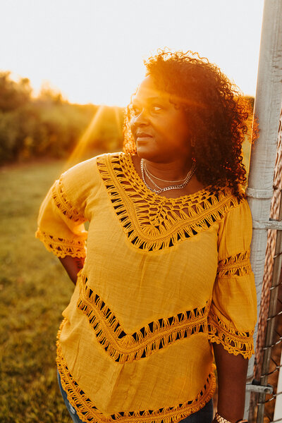 Black women in a yellow shirt with sun flare by her right eyes
