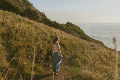 girl in white dress standing next to waterfall in columbia river gorge