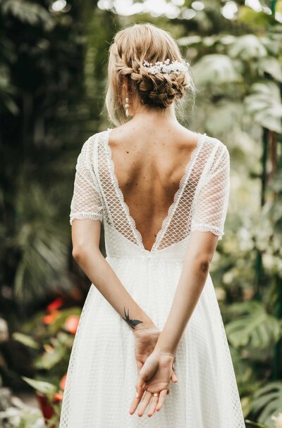 A bohemian bride walking through a botanical garden.