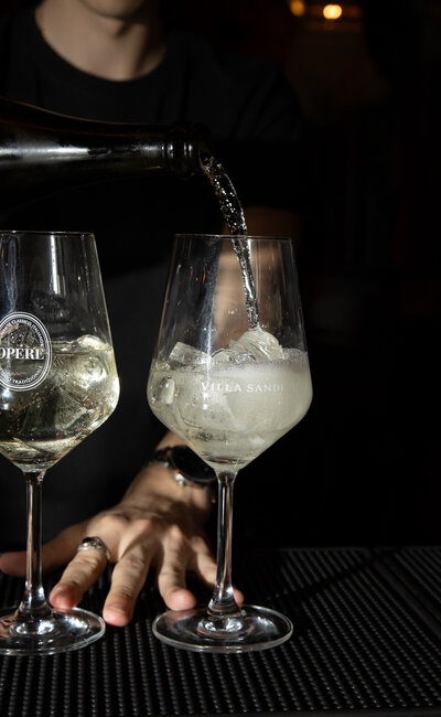 Two glasses of prosecco being poured.