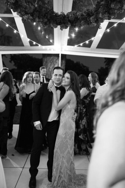 black and white photo of bride and groom at their wedding reception with guests around taken by tom thornton photography in minnesota