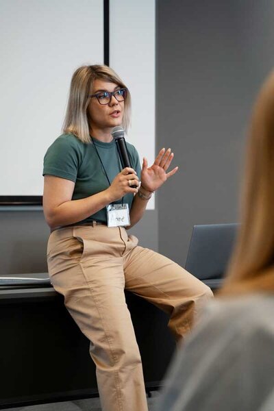 woman lean on desk speak into a microphone