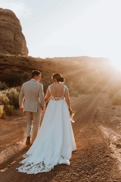 Bride and groom walking towards the sunset in the desert