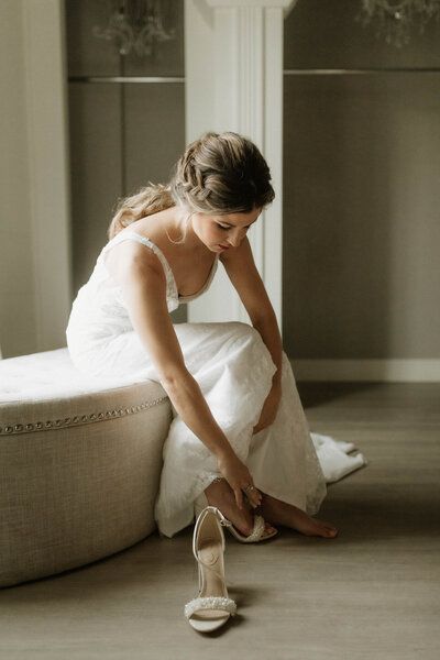 Bride Taylor adjusting her shoes before her wedding at Être Farms in Michigan City, captured in a soft, candid moment.