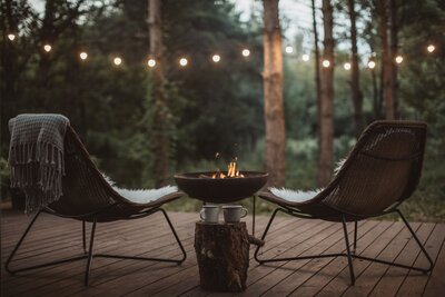 Two chairs outside a cozy home with breathtaking views of mountains and pine trees.