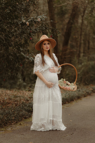 Pregnant woman in white dress with roses at the gardens by Lawrenceville Maternity Photographer