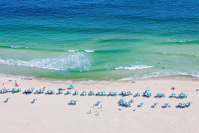 overview view of the beach in Orange Beach, Alabama on a beautiful sunny day with scattered beach chairs and blue and green water