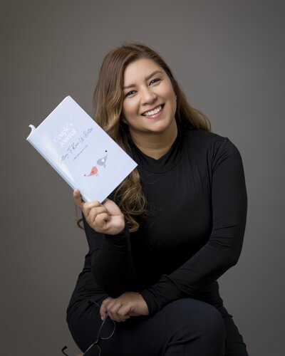 Woman, the author, of the journal holding the book and smiling