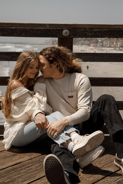 couple embraces on pier for engagement photos in san diego
