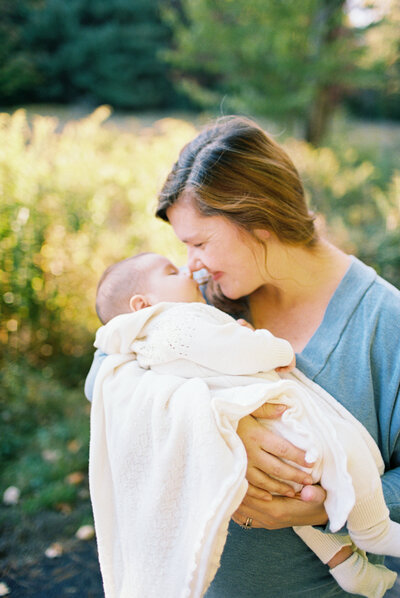 man and women sitting on bed holding baby smiling at camera