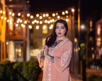 Nighttime portrait photographed by Moonlit Photo in downtown Salt Lake City, featuring a woman standing under glowing string lights with soft bokeh in the background. Warm, cinematic branding photography highlighting Utah’s urban atmosphere and editorial style.