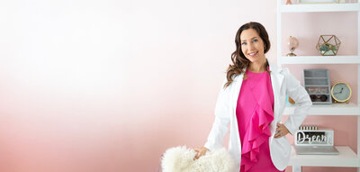 Lucy Libido smiling in Pink Dress and White Lab Coat With Pink Background