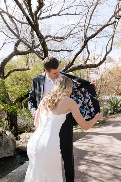 Natural neighborhood engagement session in Phoenix, Arizona of couple standing in front of pink door with greenery holding each other.