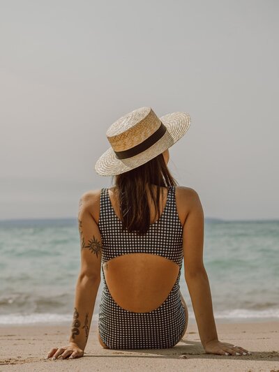 woman in a hat sitting on a beach