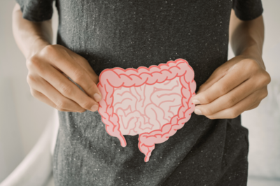 woman in gray shirt holding a paper cutout of intestines over the location of her intestines