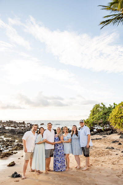 Maui Family Photographers capture mother wearing red dress holding child with flower crowns during beach family photos